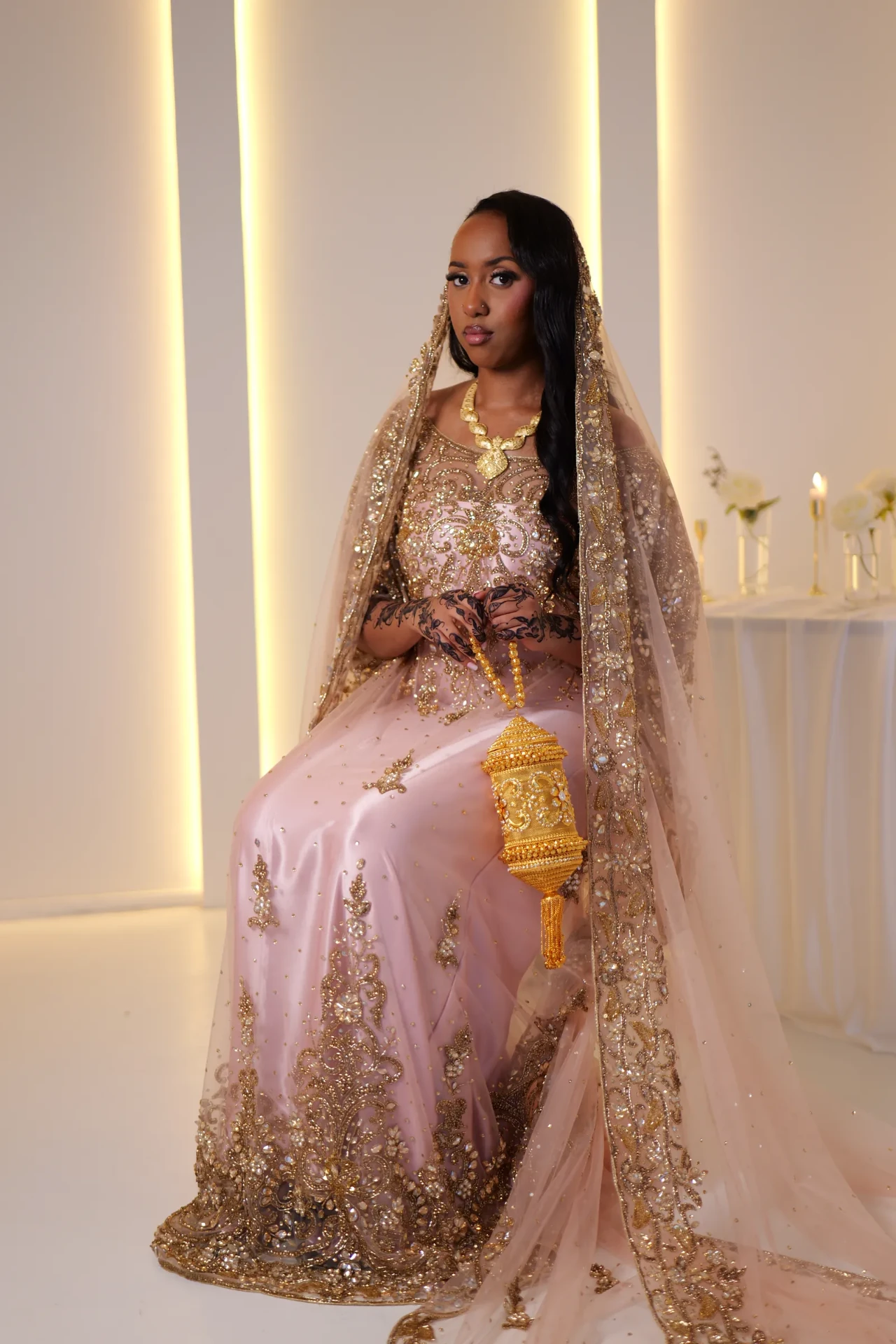 Seated view of the blush dirac, gold details and embroidered veil