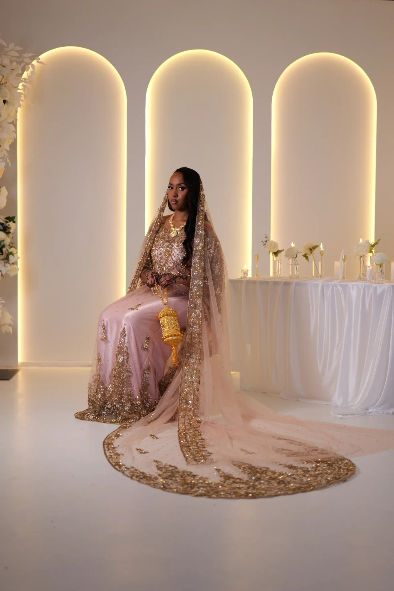Seated model in a blush dirac with the embroidered train spread across the floor