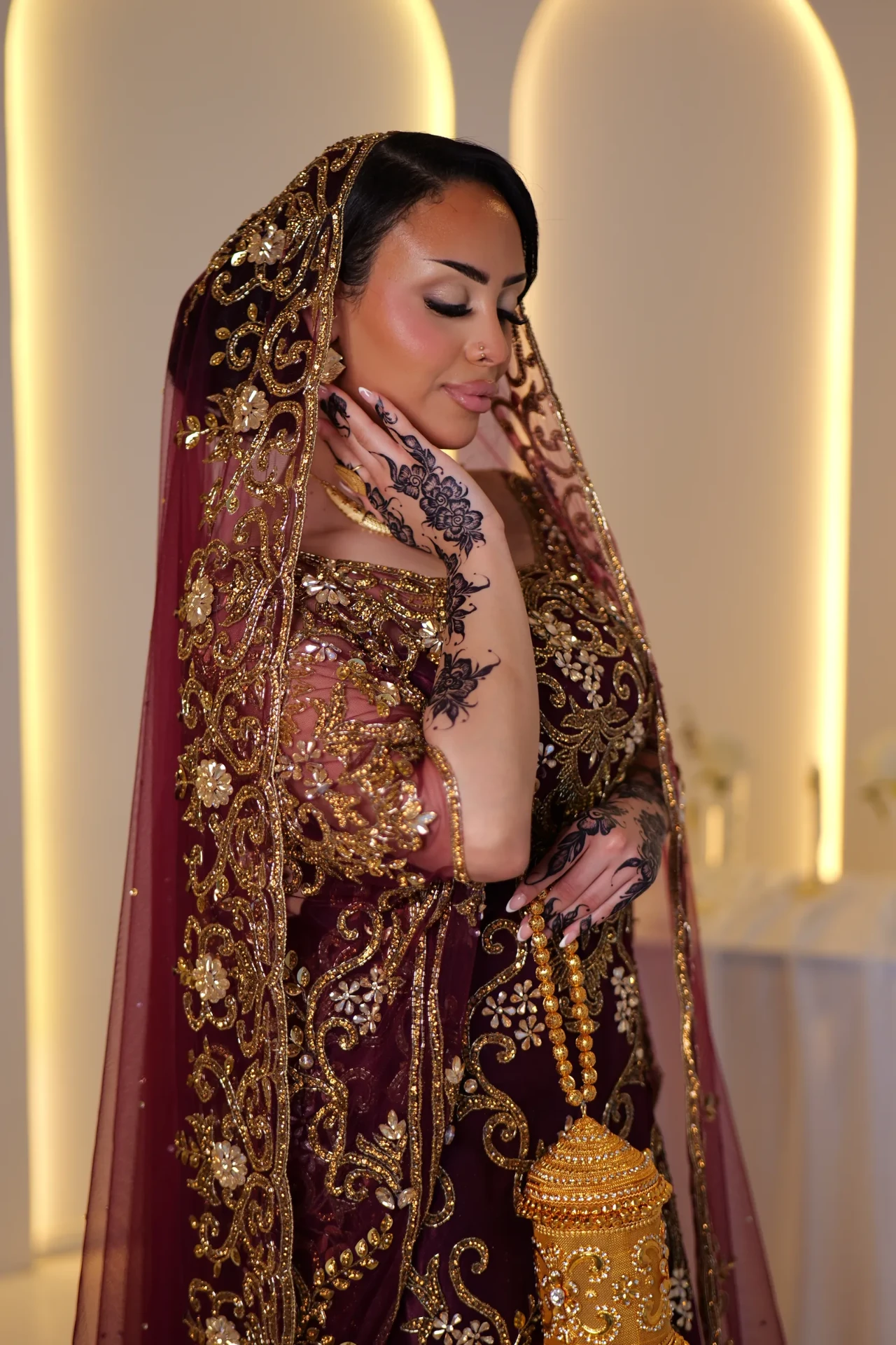 Gold lantern-shaped accessory, embroidered wine veil and henna detail